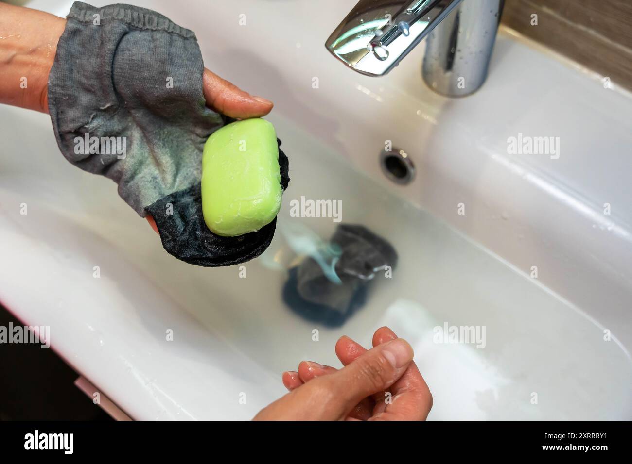 A person washes their hands in a bathroom sink with a bar of soap Stock ...