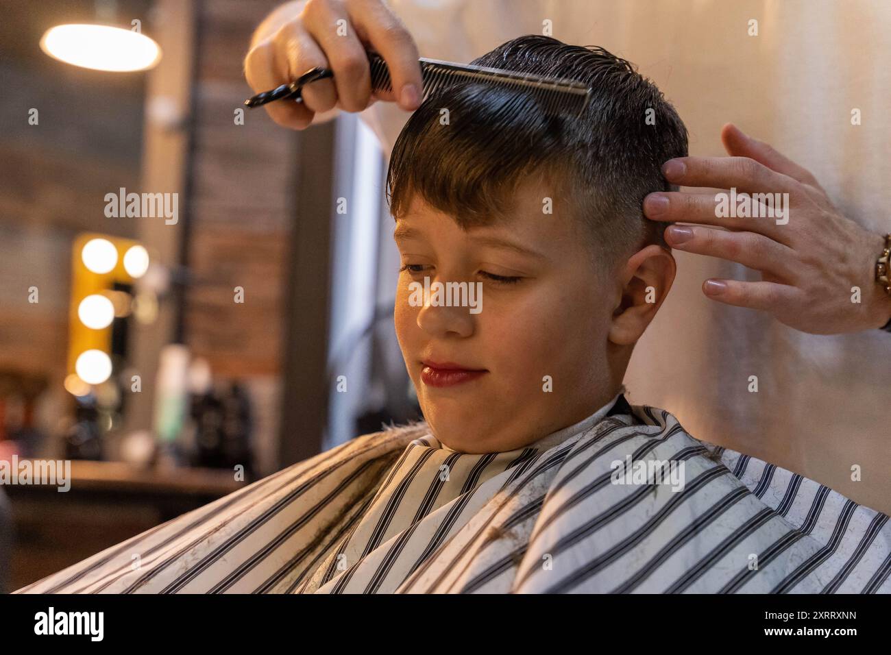 A young boy sits in a barber's chair, getting his hair cut Stock Photo ...