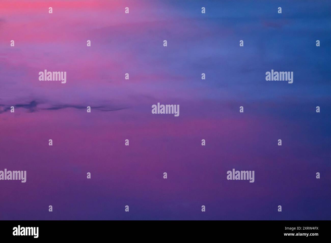 The setting sun creates an abstract pastel painting of sky and clouds. Stock Photo