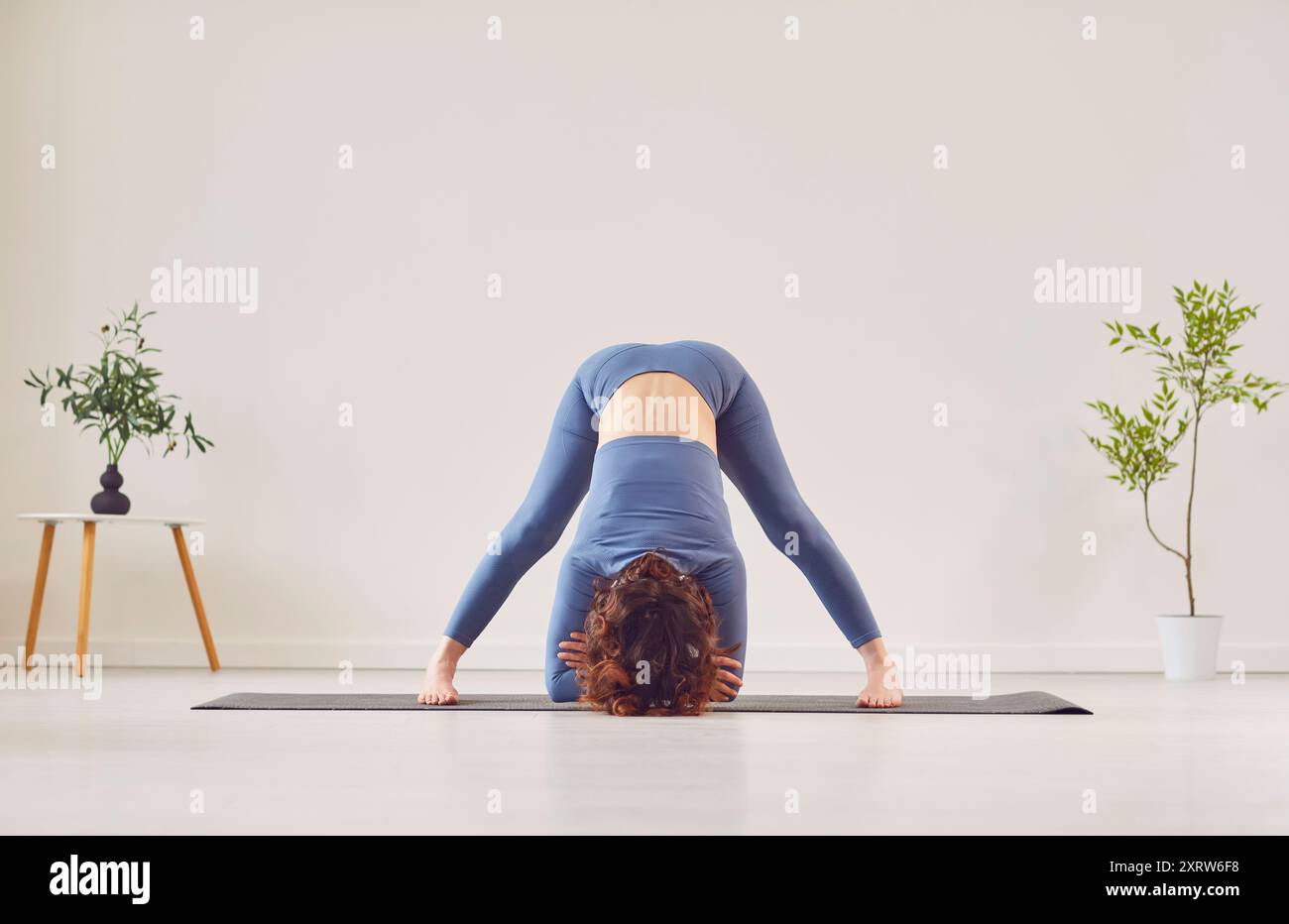 Yogi woman in sportswear doing Downward Facing Dog or Adho Mukha Shvanasana pose Stock Photo