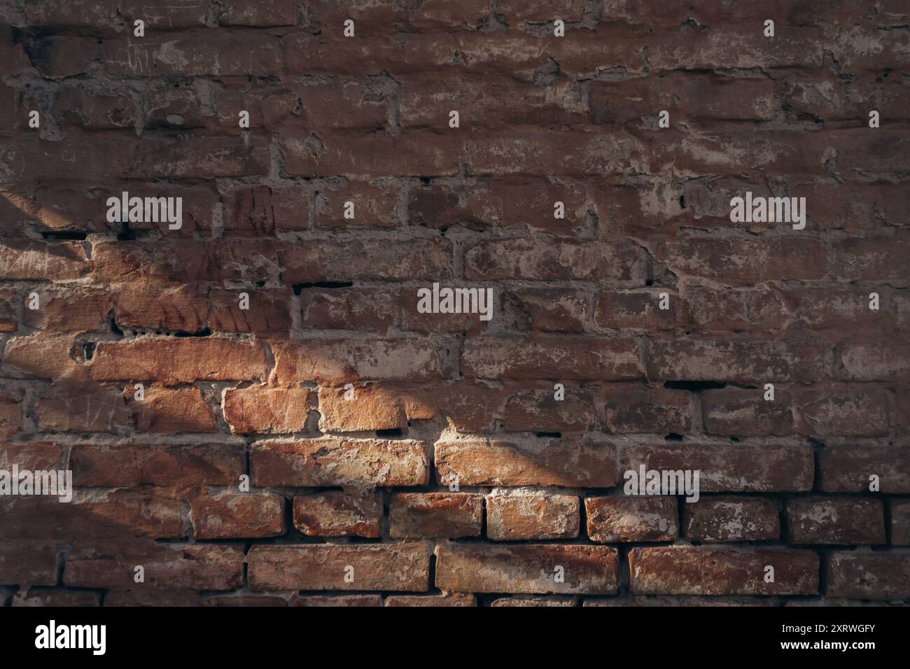 A brick wall with a shadow on it. The wall is old and has a rough texture. The shadow is cast on the wall, creating a sense of depth and dimension. Sc Stock Photo