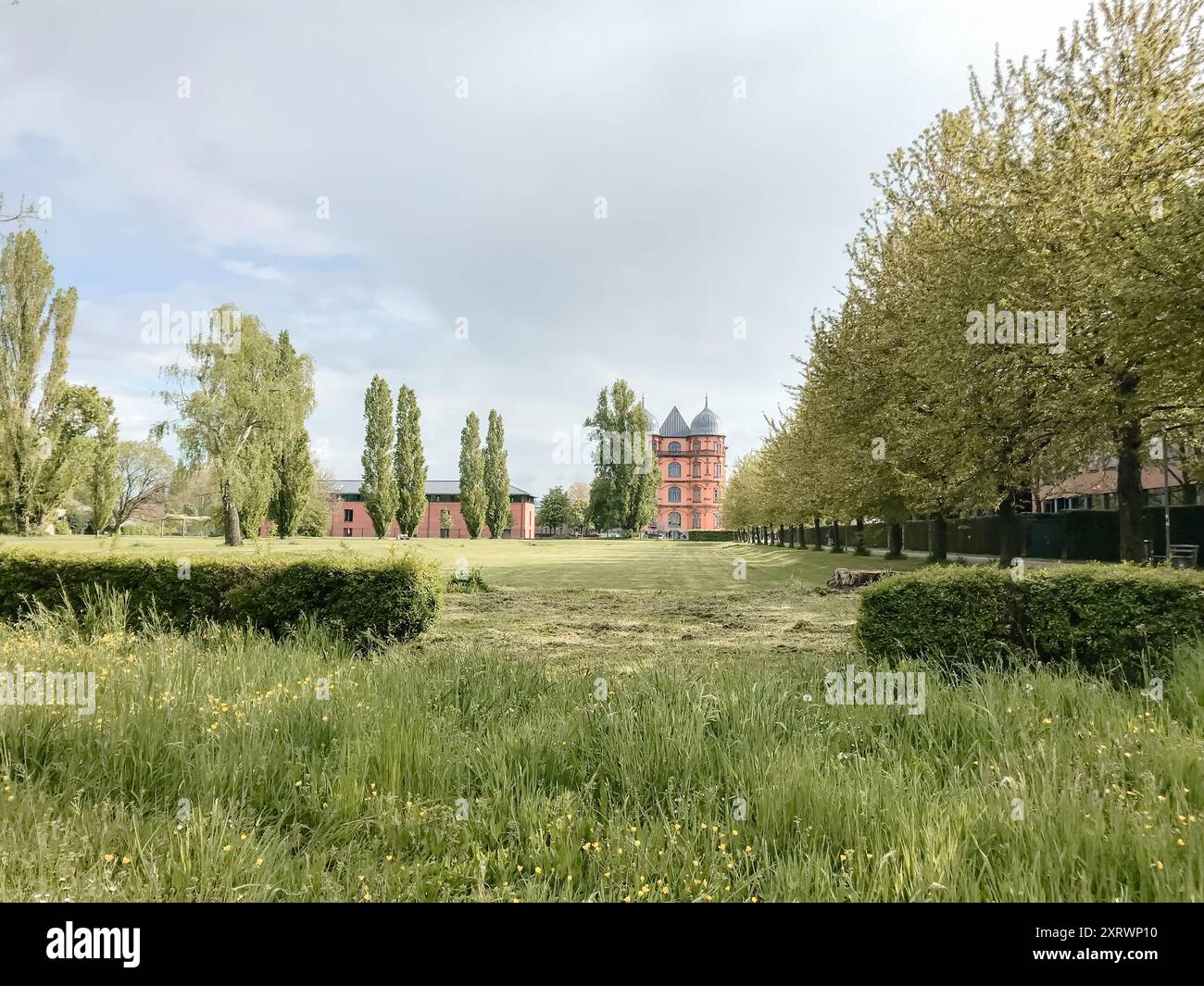 Building Ina Field A large red building sits in a field with trees and grass. The building ...