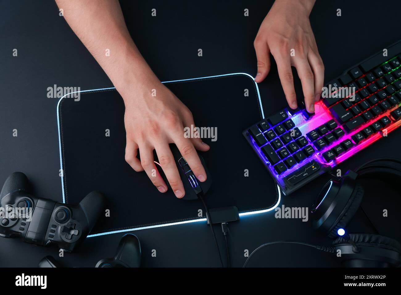 Gamer using modern wired computer mouse at black table, top view Stock Photo