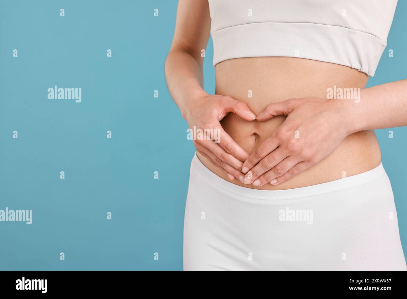 Healthy digestion. Woman making heart shape with hands near her belly ...