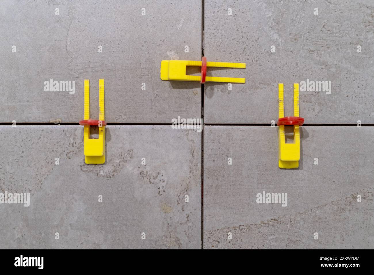 Tile installation using plastic leveling clips and wedges. Ensuring a smooth Stock Photo