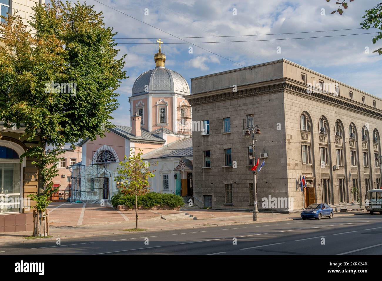 The old Soviet building and the Orthodox Church in the city of Kursk, Russia, during the cloudy summer afternoon. Stock Photo