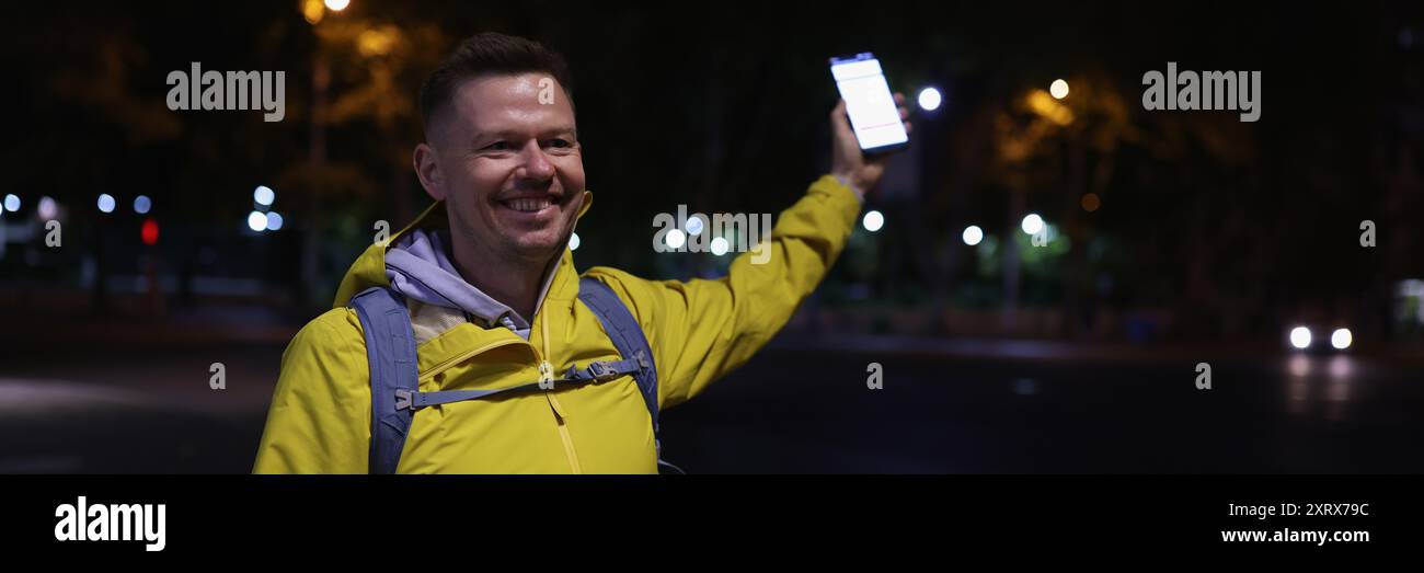 Man in yellow coat holding mobile phone in hand Stock Photo
