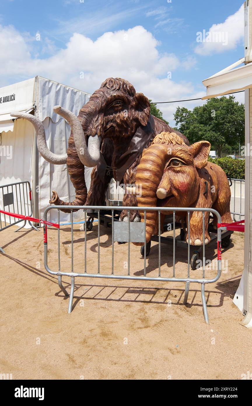 Viladecasn, SPAIN - AUGUST 12, 2024: Life-sized mammoth models draw attention at the Sant Isidro Fair against a backdrop of white tents and partly clo Stock Photo