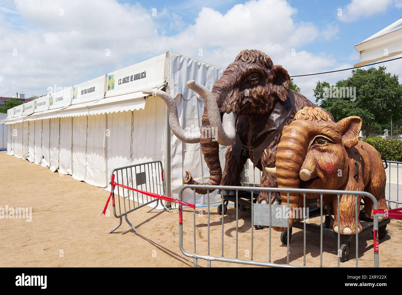 Viladecasn, SPAIN - AUGUST 12, 2024: Mammoth replicas at the Sant Isidro Fair in Viladecans, with white tents and partly cloudy skies in the backgroun Stock Photo