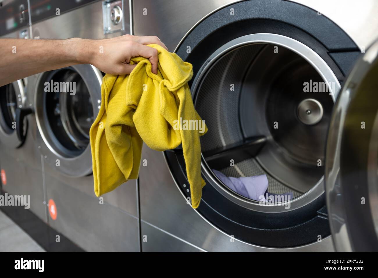 Unrecognizable man operating using washing machine at commercial laundry Stock Photo
