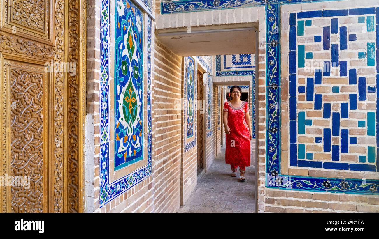 Local woman in red dress in the historical building of Registan Square in Samarkand, Uzbekistan. Stock Photo