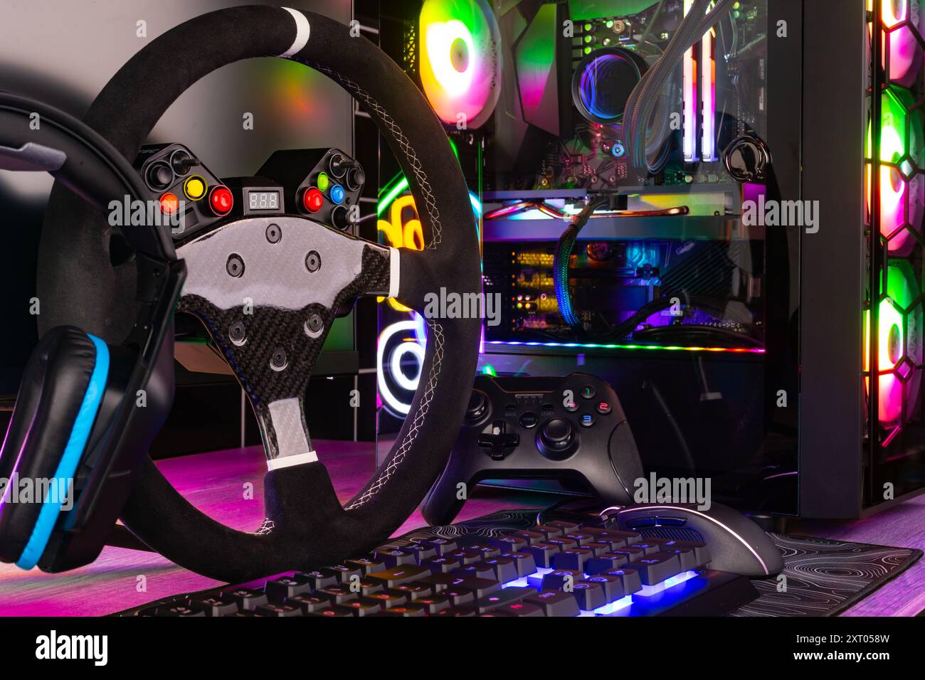 colorful gaming pc desk with bright raimbow led computer gamepad mouse keyboard and steering wheel. esports video games concept  background Stock Photo