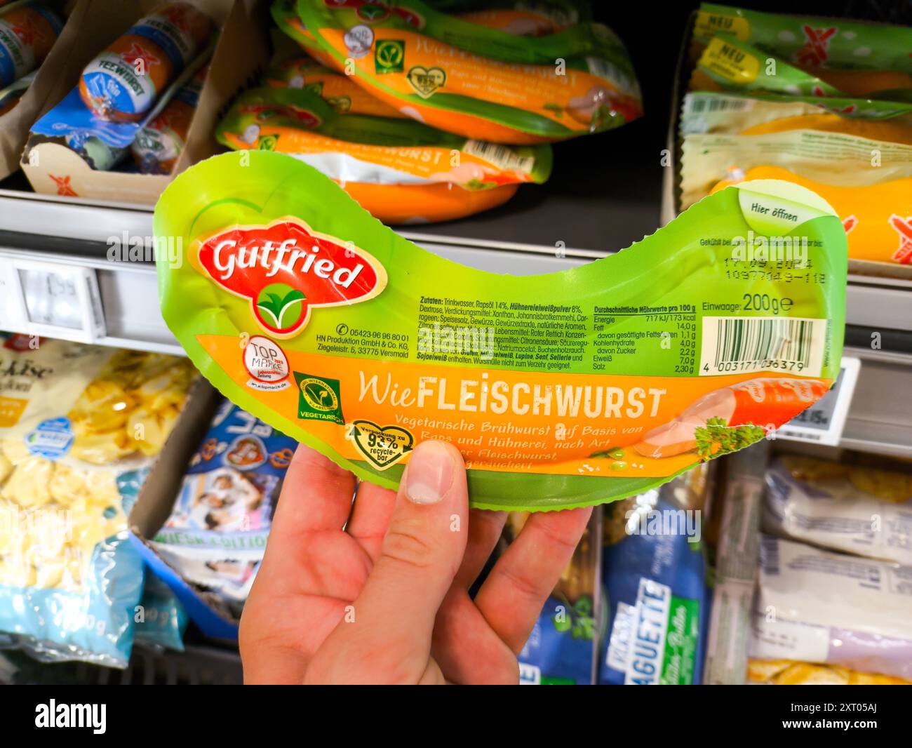 Bavaria, Germany - August 12, 2024: Vegetarian meat sausage from Gutried, a plant-based alternative to conventional sausage, is held in a customer s hand in the supermarket s refrigerated section *** Vegetarische Fleischwurst von Gutried, eine pflanzliche Alternative zu herkömmlicher Wurst hält ein Kunde in der Hand im Kühlregal vom Supermarkt Stock Photo