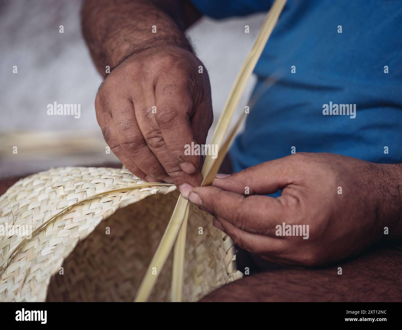 Close-up view of an artisan's hands meticulously weaving a traditional ...
