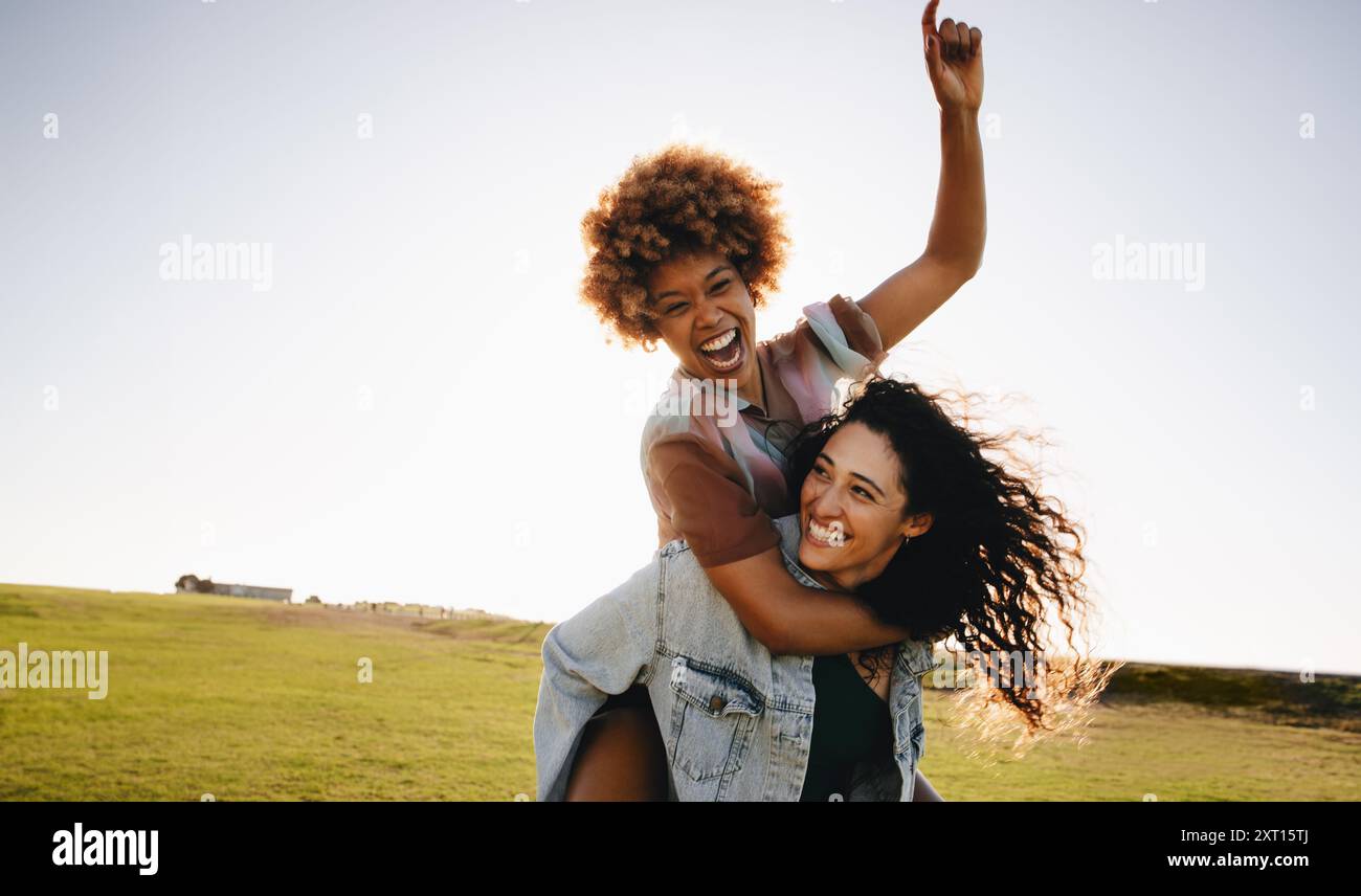 Playful friends experiencing joy and laughter outdoors, enjoying time together on a sunny day, highlighting friendship and happiness. Stock Photo