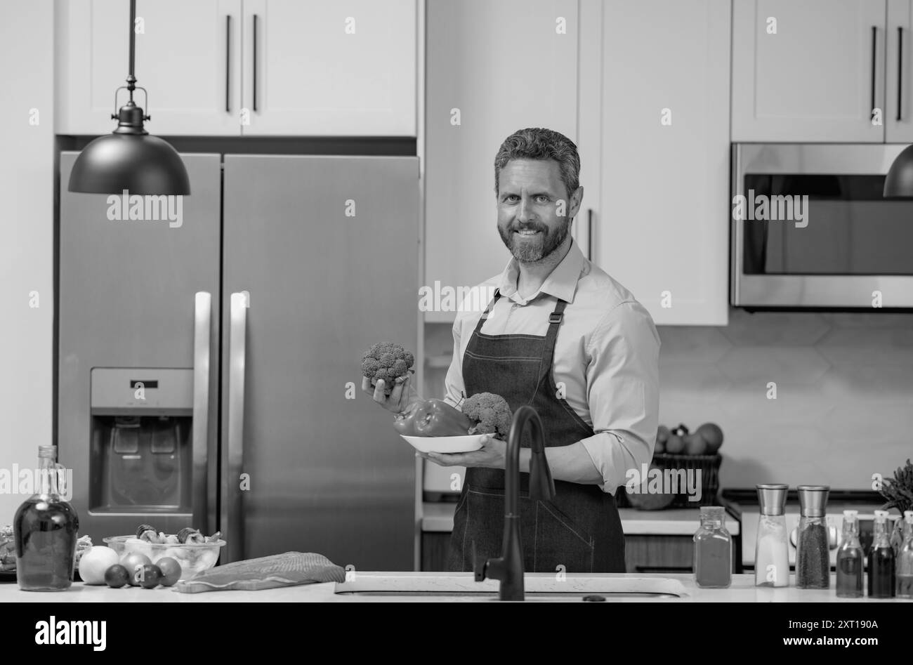 Chef in cook apron cooking in kitchen. Man on kitchen with vegetables ...