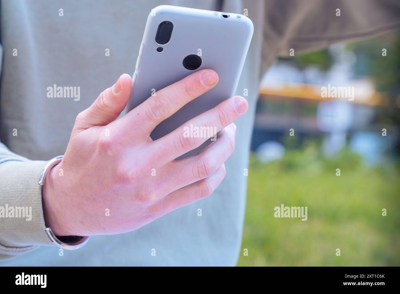 Unrecognizable man browsing the internet using mobile device outdoors. Stock Photo