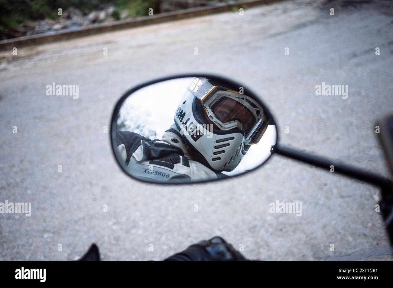 Reflection of a motorcyclist wearing a helmet and goggles in a motorcycle s rearview mirror on a road. HaGiang Vietnam rist00098 Copyright: xConnectxI Stock Photo
