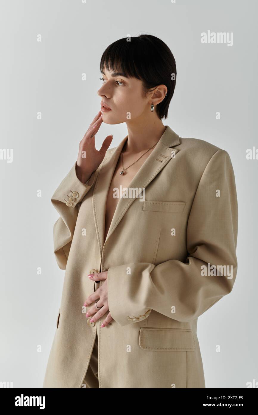 A woman poses in a tan blazer against a light background Stock Photo ...