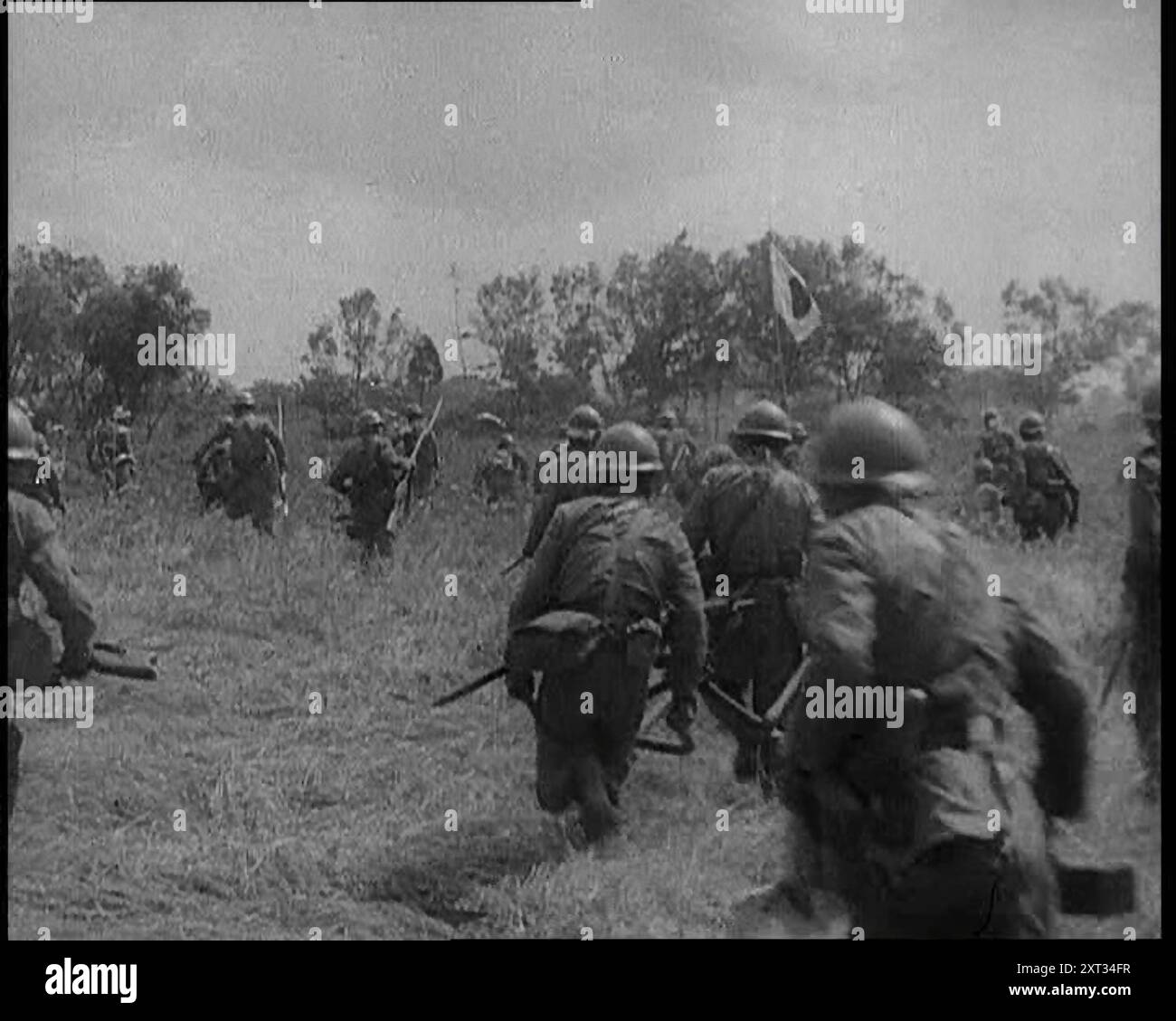 Japanese Soldiers Running Through a Field, 1933. 'Japan's forceful infiltration into Jehol [Rehe Province, China], coming so soon after her Manchurian annexation, put before the League of Nations a test case'. From &quot;Time To Remember -  The Time Of The Monster&quot;, 1933  (Reel 3); a documentary film about events of 1933, rise of Roosevelt and Hitler. Stock Photo