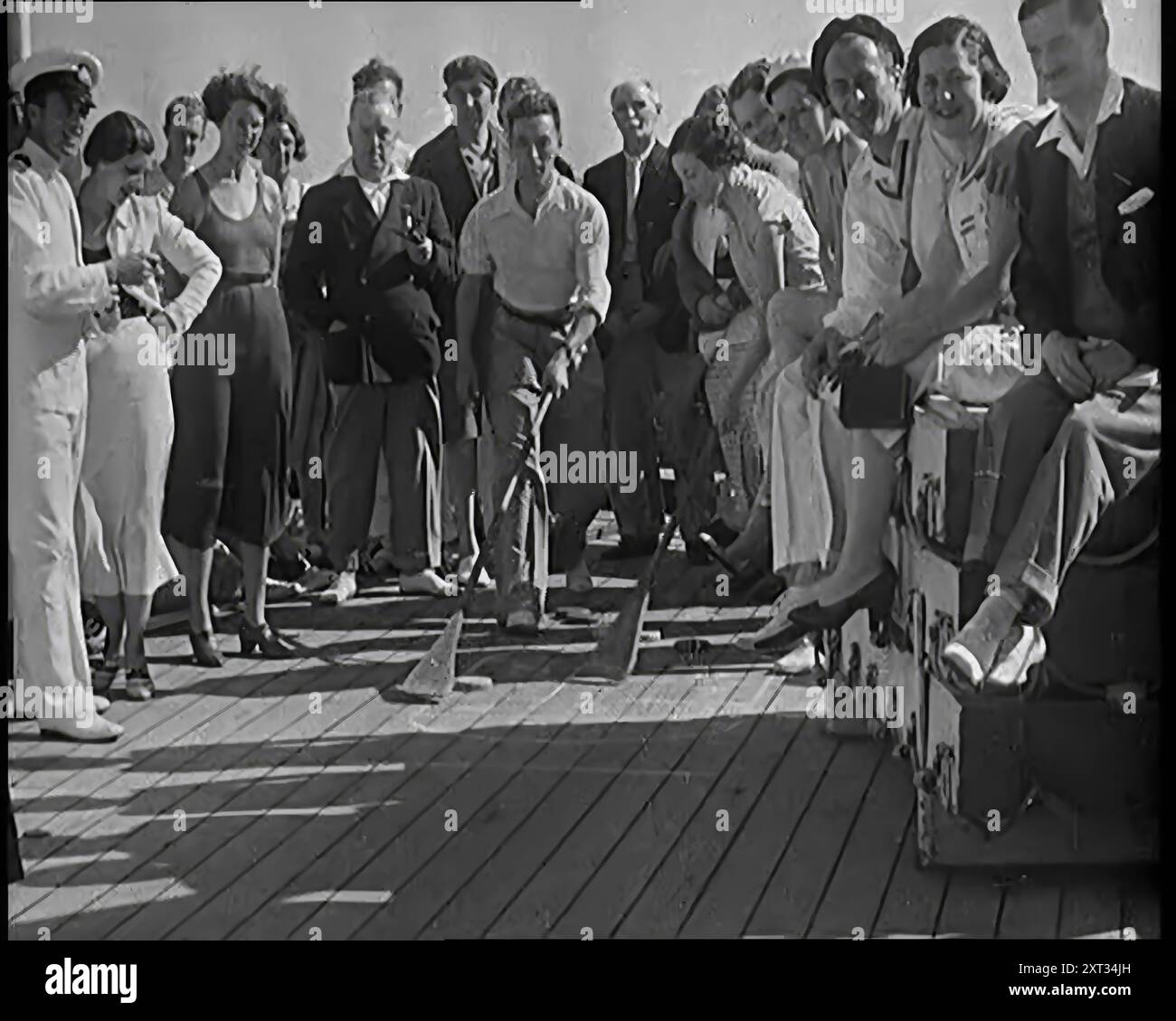 People Enjoying Games on Deck of a Cruise Liner Whilst at Sea, 1931. 'The world shipping slump brought its compensations. To keep their liners in commission, companies inaugurated the first, but the very first, cruises. Some advertised rates at only &#xa3;1 a day. Cruises were one long party, with the added attraction of visits to foreign ports and places that otherwise you'd never have a hope of seeing. Suddenly ships' officers found themselves comperes in one endless variety show, organising deck games, swimming galas and beauty contests. Yes, for &#xa3;1 a day it was certainly a full life w Stock Photo