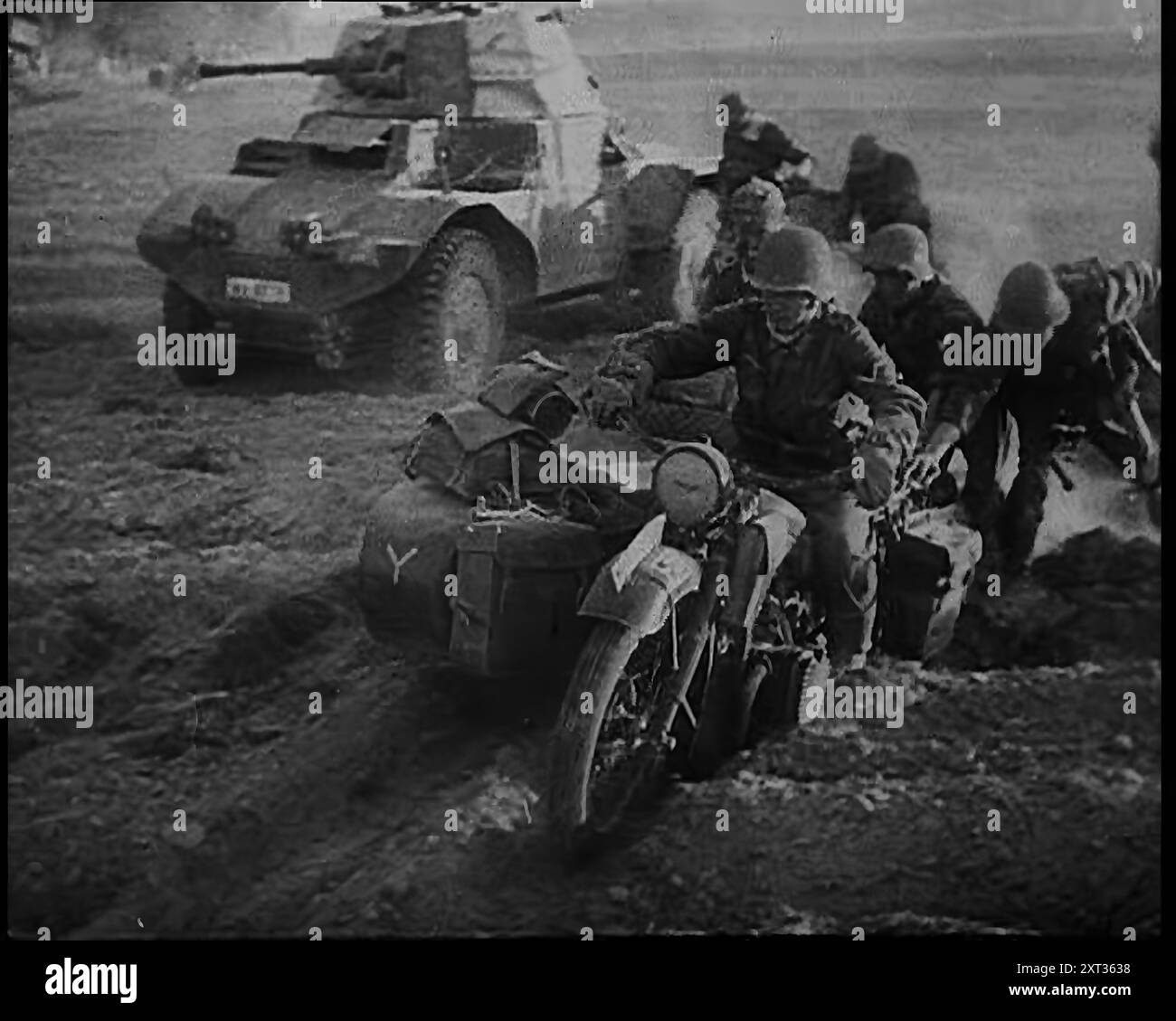 German Soldiers Advancing Through Dusty Fields on Military Vehicles To Cut Off Allied Units in France, 1940. Second World War. 'Now, through a gap fifty miles wide, Army Group A drives to sever the Allied armies in two, hellbent on reaching the Channel coast. If the roads are blocked, whole divisions and their armour take to the fields, hardly even pausing as they shoot up enemy units in the woods while passing'. From &quot;Time To Remember -  Run Rabbit Run&quot;, 1940 ( Reel 3); documentary film about events of early months of 1940. Stock Photo