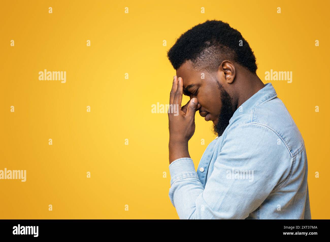 Profile portrait of depressed black guy touching his forehead Stock Photo