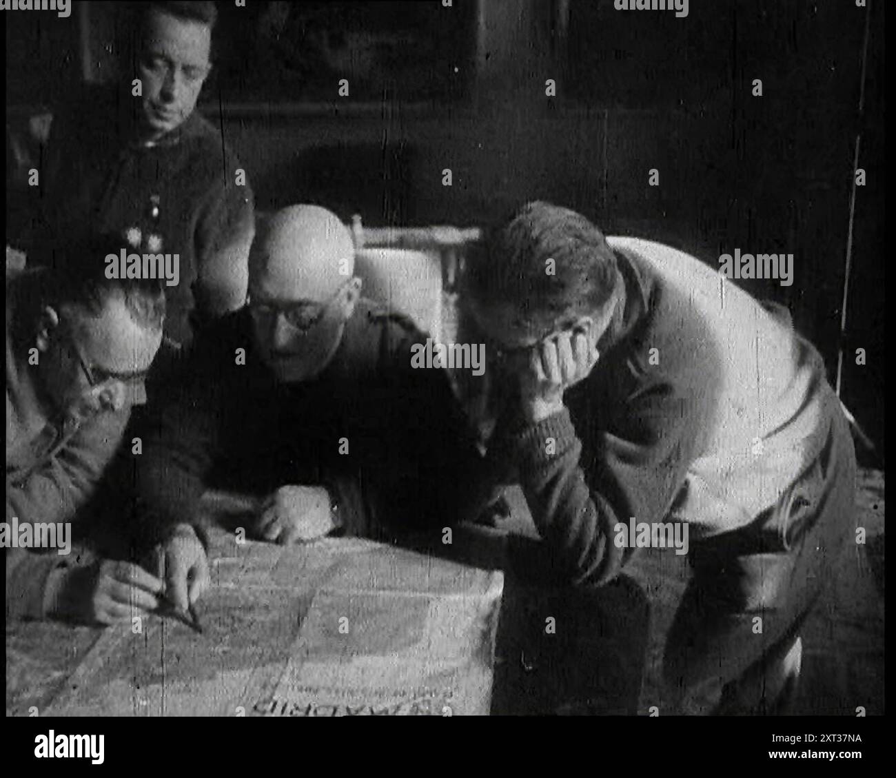 Four Men Consulting a Map in an Office, 1937. Spanish Civil War. '...there was - alas - plenty of trouble...at large in Europe, particularly in places like Madrid. For the cities of Spain were the first to feel the breath of war in a truly modern manner. It has been said that war is but an extension of politics. True enough, particularly if it happens to be a civil war...For this was a war in which all people were soldiers, for the soldiers were the people. You just did what you were told, and fought'. From &quot;Time To Remember -  Sense Of Values&quot;, 1937 (Reel 2); documentary film about Stock Photo