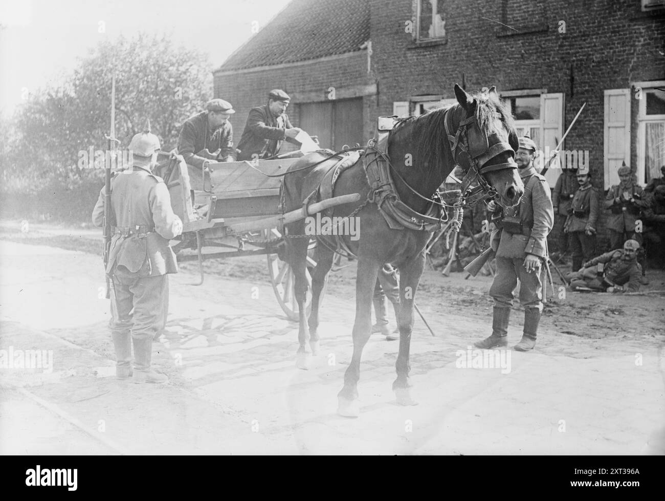 Belgian peasants showing pass to sentries, between 1914 and c1915. Shows Belgian men in a horse-drawn cart, showing a pass to German soldiers during World War I. Stock Photo