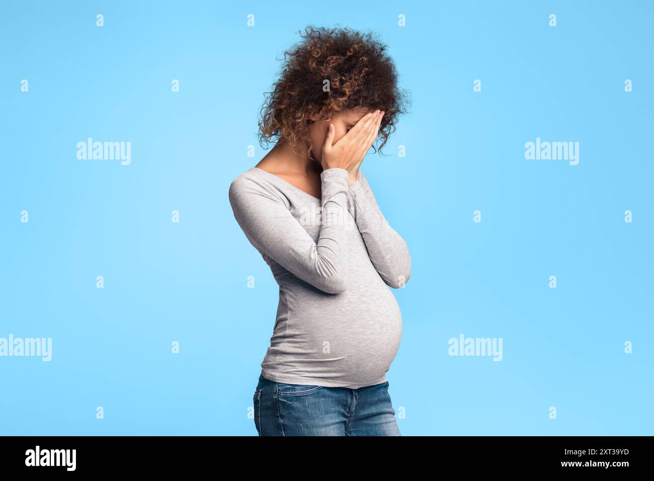 Depressed expectant lady closing her face and crying Stock Photo