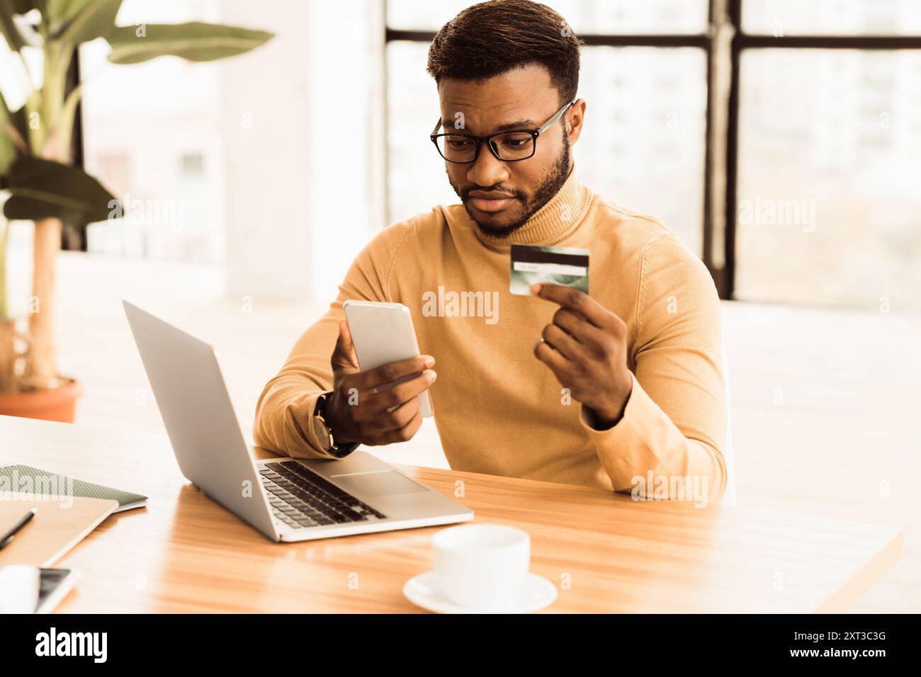 Black manager making purchases using computer and phone Stock Photo