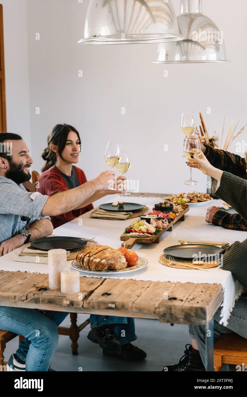 Friends gathered around a rustic wooden table enjoying a meal and ...