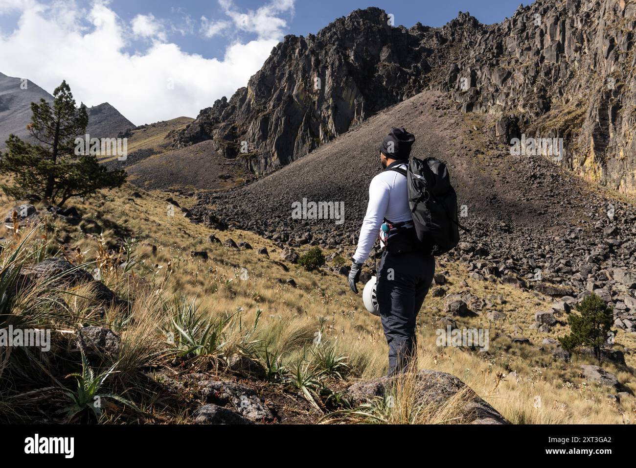 Back view of an unrecognizable male hiker gazing at the steep rocky slopes of a dormant volcano in Mexico, showcasing the majestic and challenging lan Stock Photo