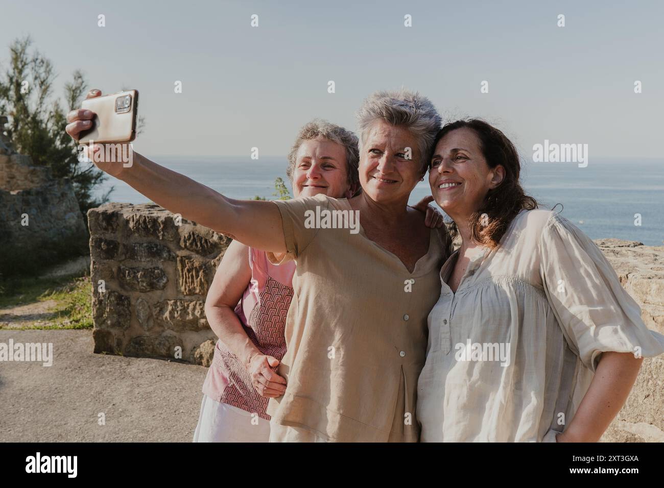 Three elderly women smile as they take a selfie with a smartphone by a ...