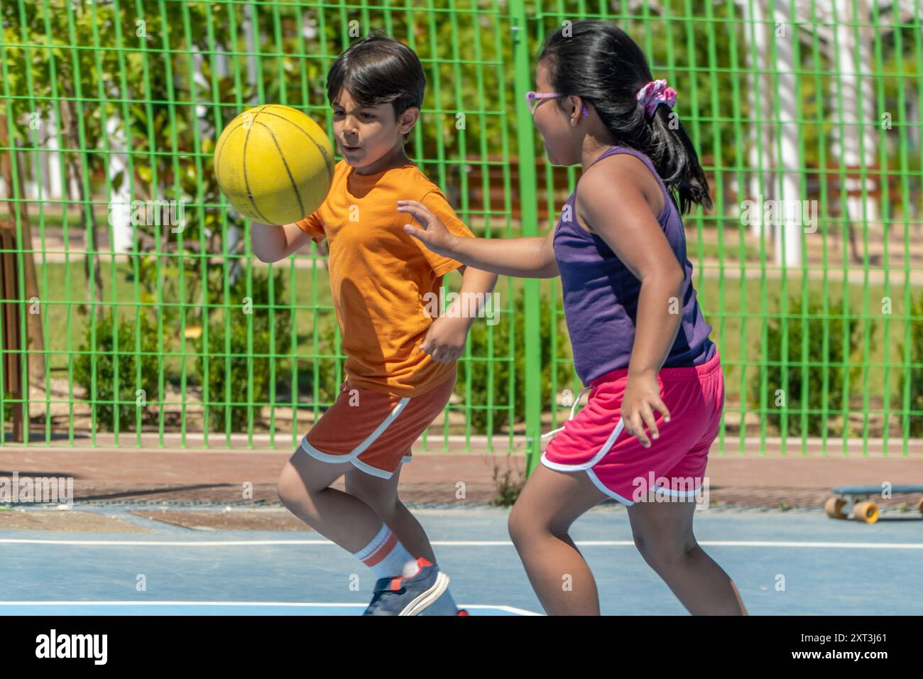 Yball A young boy and girl engage in a playful game of basketball on an ...