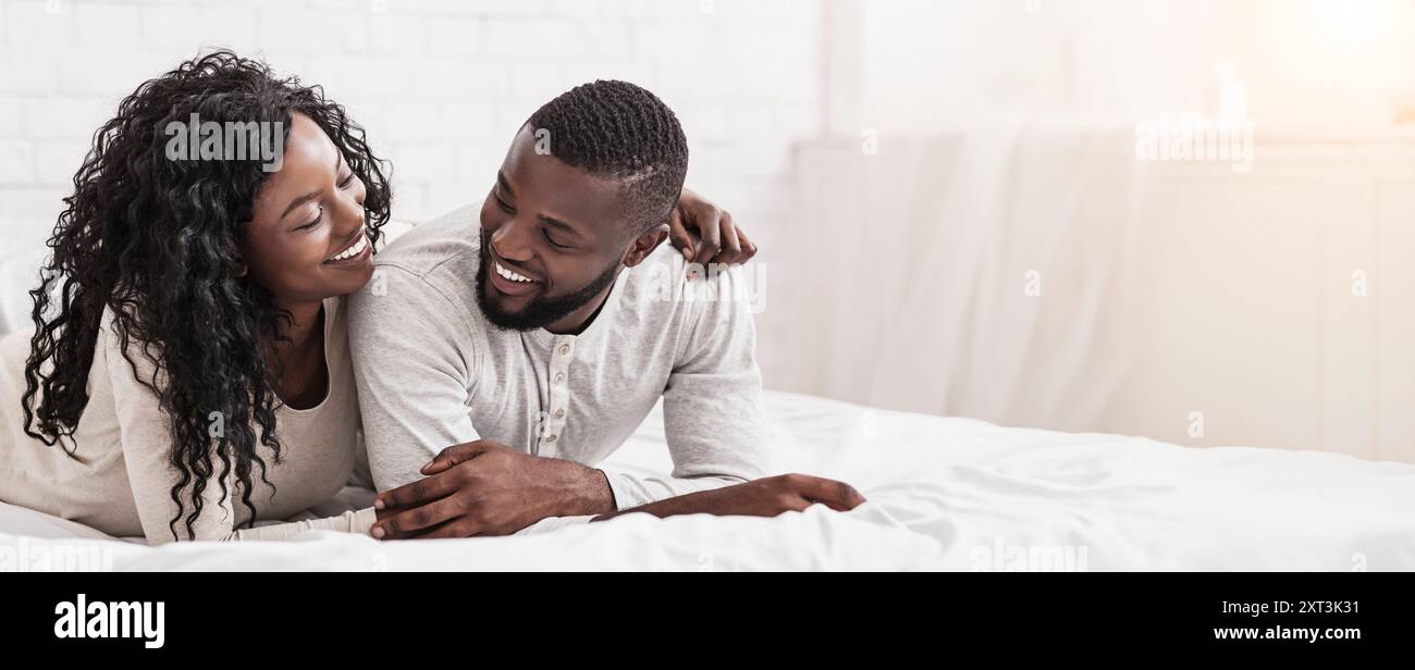 Romantic african american couple cuddling on bed at home Stock Photo ...