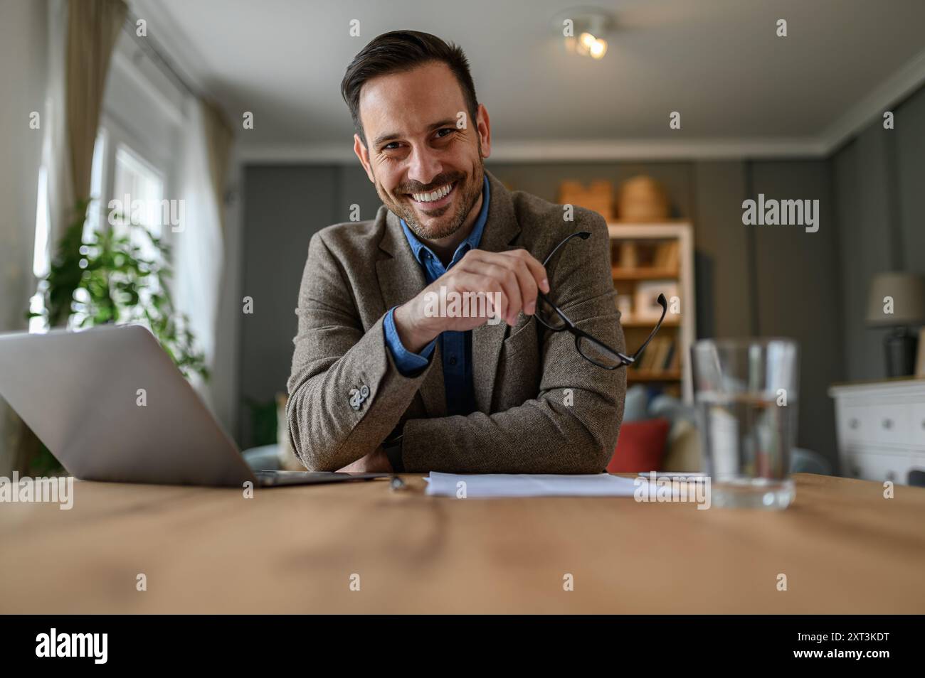 Low angle portrait of smiling businessman in elegant suit holding ...
