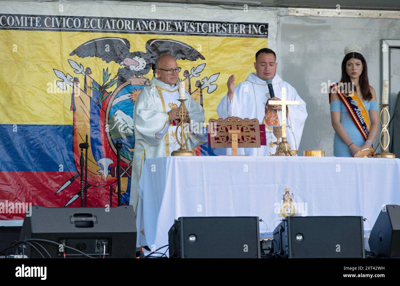 2 Catholic priests and a beauty queen on stage for a communion service prior to the starrt of the Ecuadorian Heritage festival in Westchester, New Yor Stock Photo
