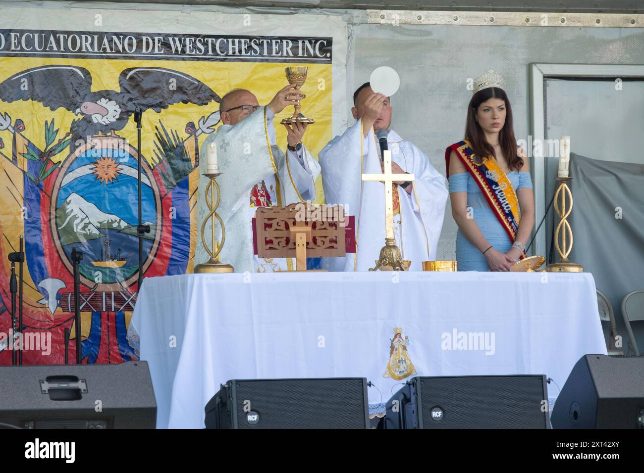 2 Catholic priests and a beauty queen on stage for a communion service prior to the starrt of the Ecuadorian Heritage festival in Westchester, New Yor Stock Photo