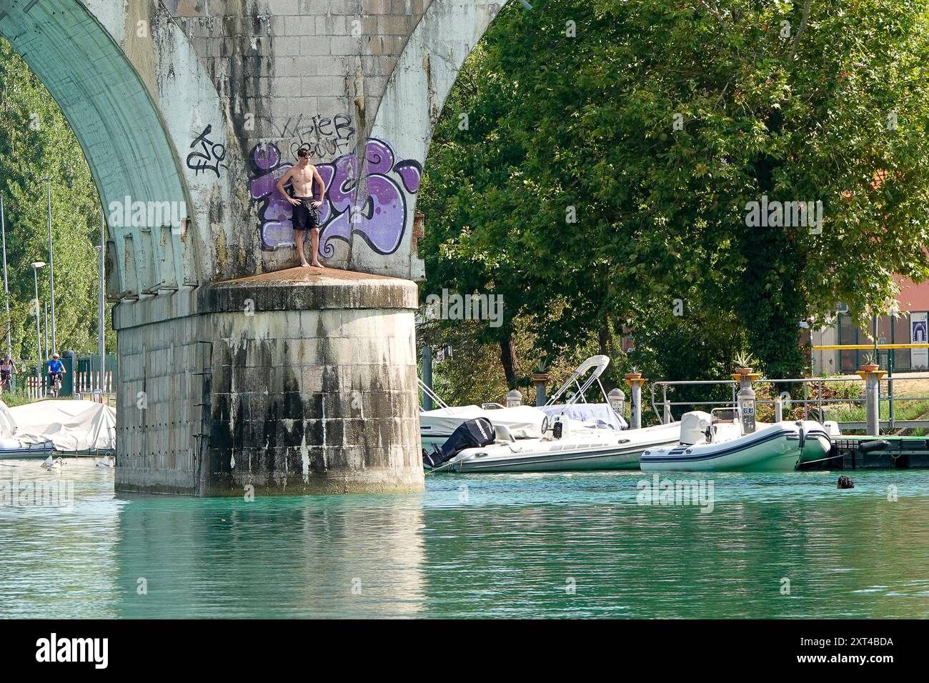 Fiume Mincio, Peschiera del Garda. 13th August 2024. Heatwave conditions persisted across much of Europe today, including Lake Garda and surrounds in Northern Italy. Daytime temperatures were expected to reach 37 degrees Celsius in the shade today. People trying to stay cool at Peschiera del Garda, on the south side of Lake Garda, in Northern Italy. Credit: james jagger/Alamy Live News Stock Photo