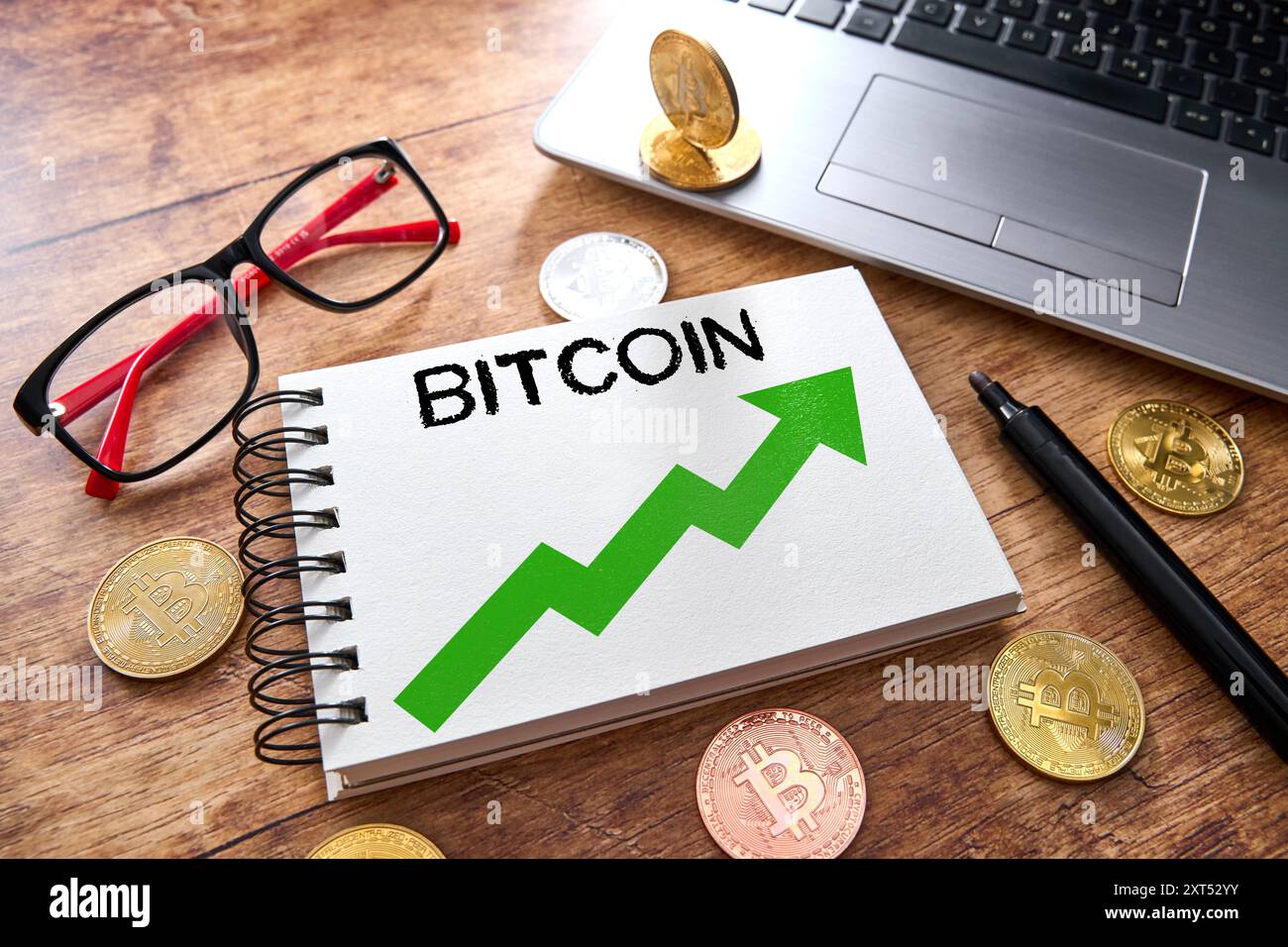 13 August 2024: Notebook with the word: Bitcoin and an upward trend, surrounded by Bitcoin coins, a pair of glasses and a laptop. Symbolic image profit with Bitcoin cryptocurrency. PHOTOMONTAGE *** Notizbuch mit dem Wort: Bitcoin und einem Aufwärtstrend, umgeben von Bitcoin-Münzen, einer Brille und einem Laptop. Symbolbild Gewinn mit Bitcoin Kryptowährung. FOTOMONTAGE Stock Photo