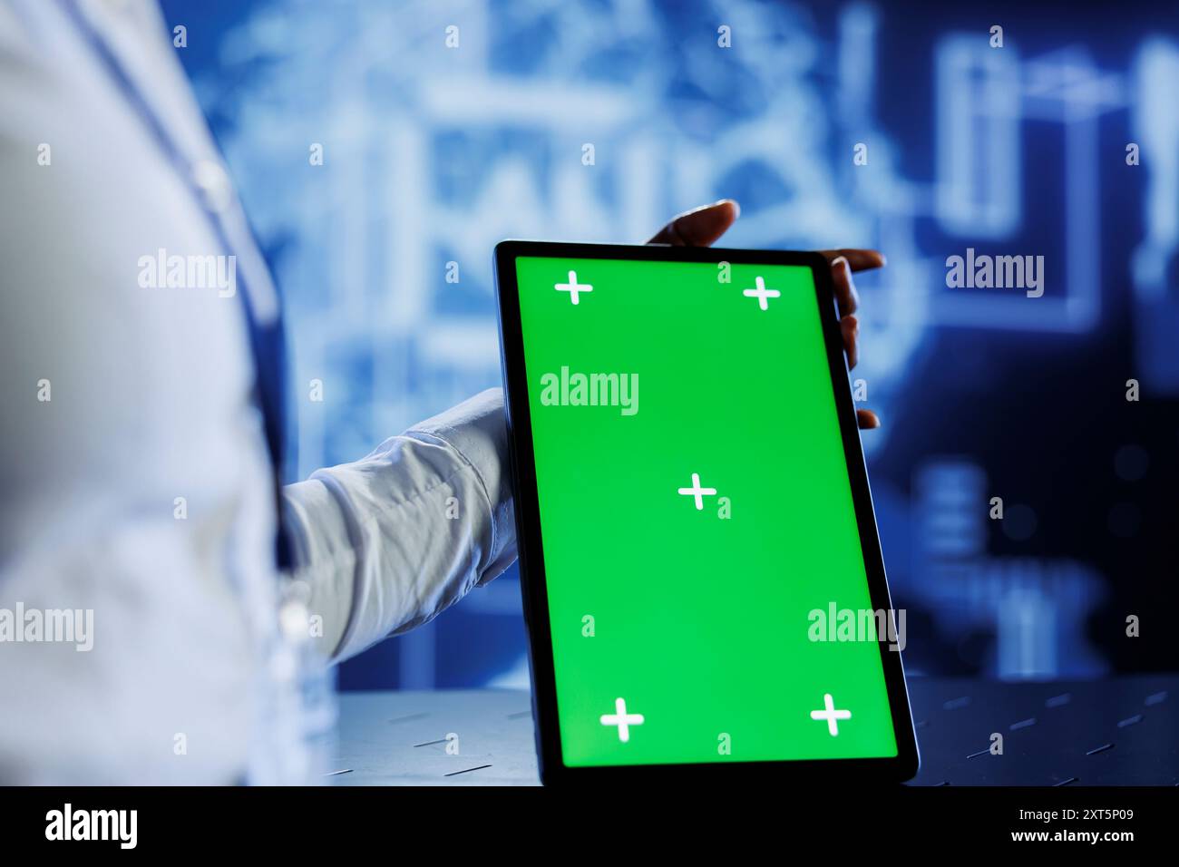 IT consultant uses green screen tablet to update neural networks, writing intricate binary code scripts on tablet. Worker uses chrome key device programming to upgrade AI simulation model Stock Photo