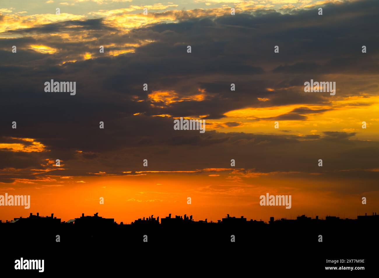 Cloudy sunset sky over the city rooftops. The last rays of the already set sun beautifully color the sky Stock Photo