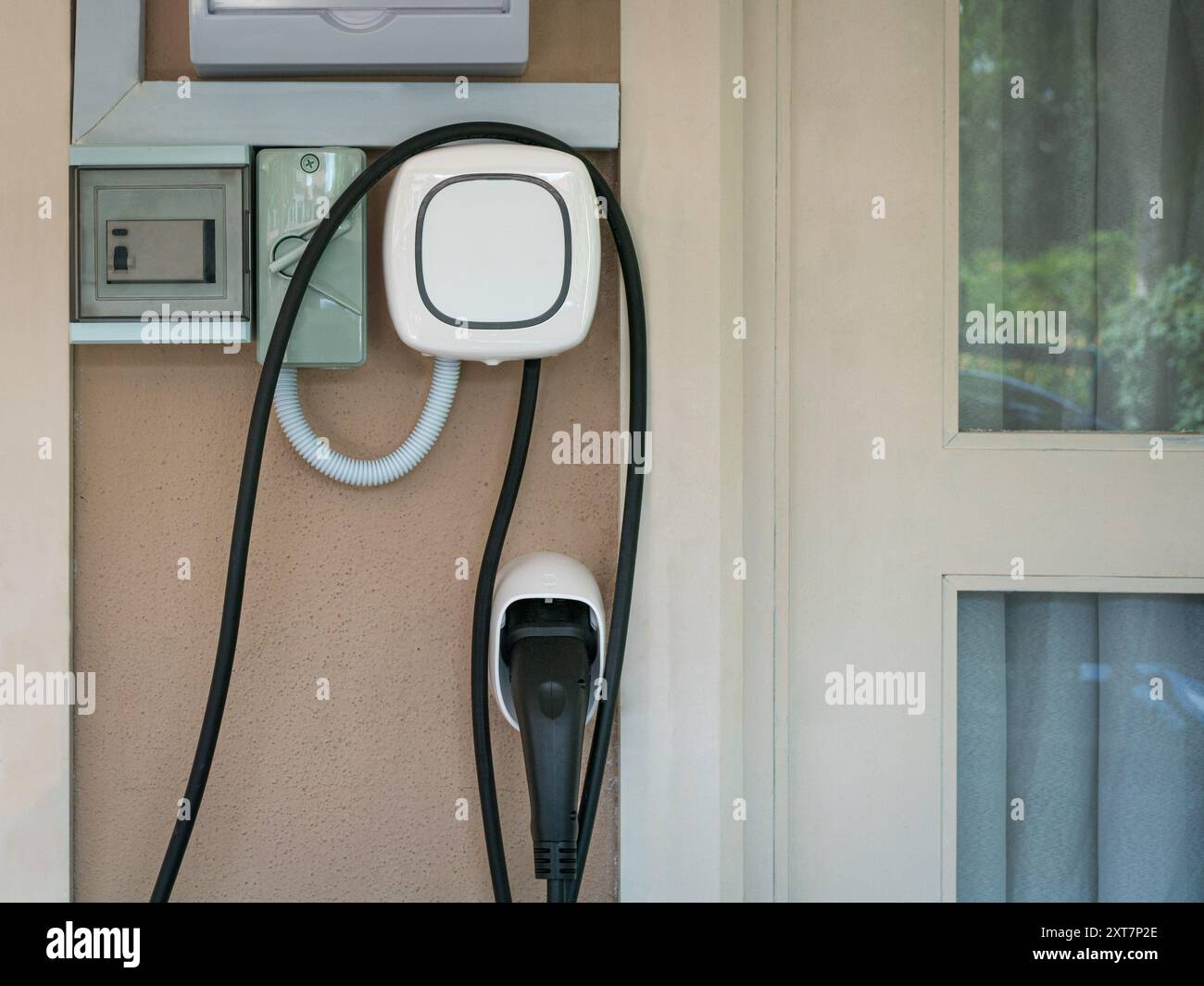 Wall charging station for electric car installed in a residential house. Stock Photo