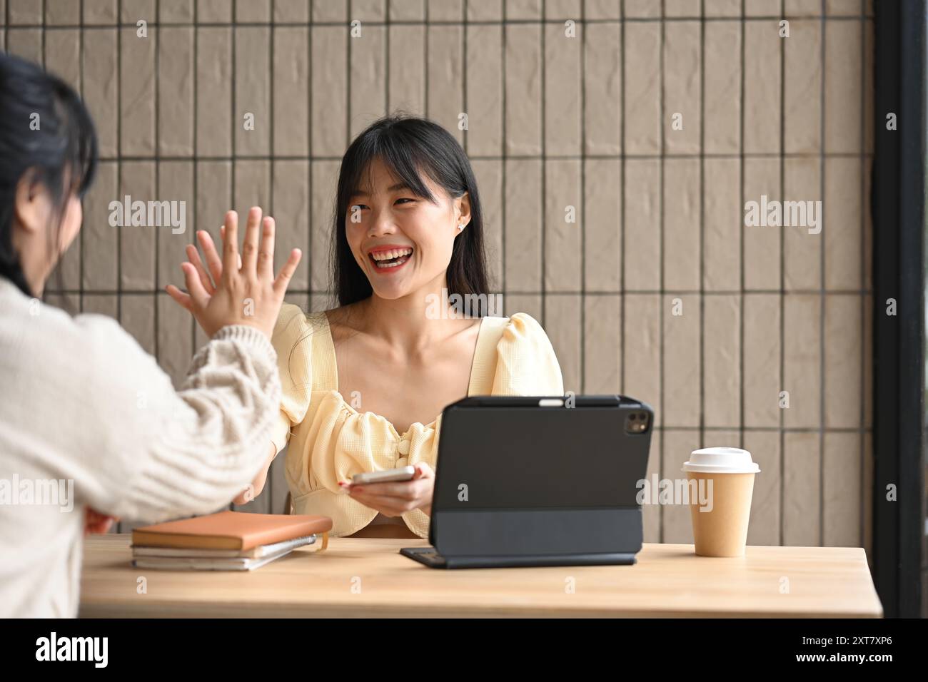 Two happy young female colleagues giving high five in the office ...