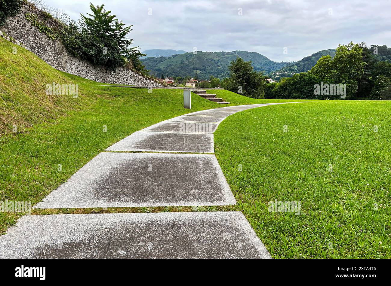 Road of large stones surrounded by green grass with mountains in the background in Asturias. Stock Photo