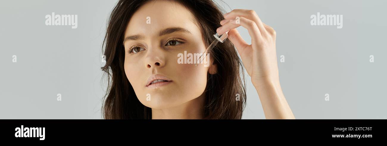 A woman applies serum to her face. Stock Photo