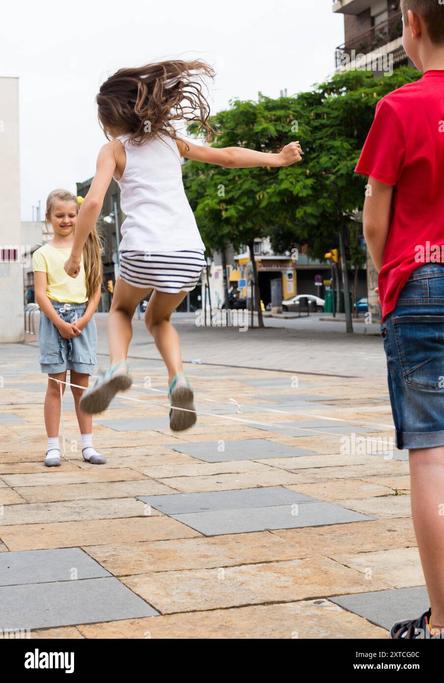 Blonde Girl jumps over rope on the sidewalk in the city in summer Stock ...