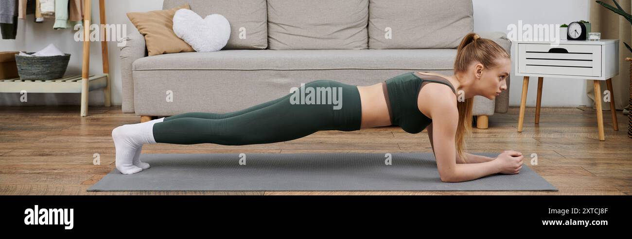 A young woman performs a plank exercise on a yoga mat in her living ...