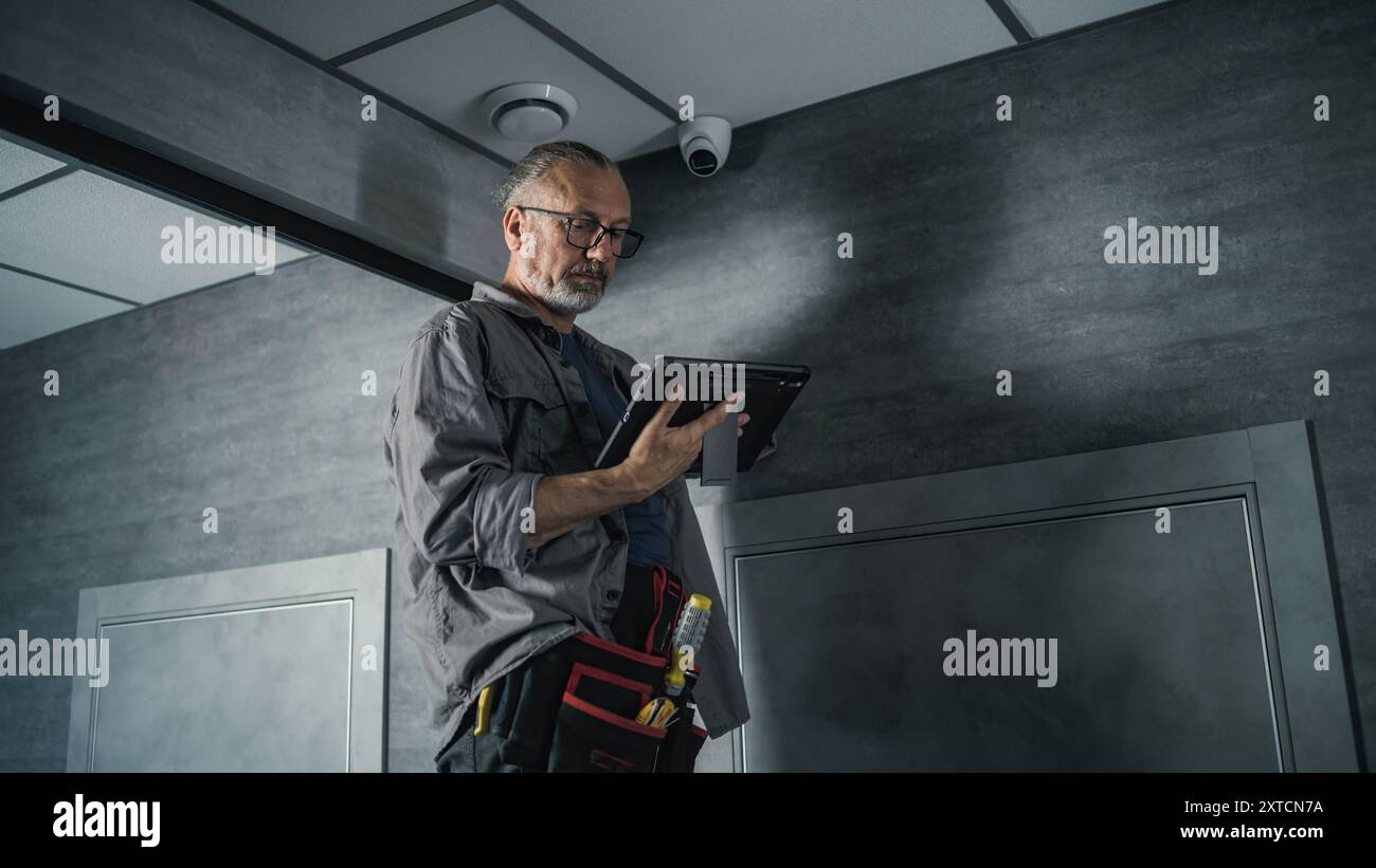 Male installer adjusts the angle of CCTV camera in office, sets up it ...